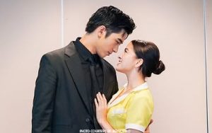Couple in formal attire gazing into each other's eyes, hands gently touching, conveying romance.