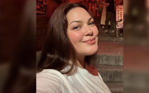 Woman smiling at the camera during a nighttime outdoor selfie on stone steps.